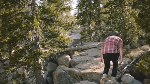 Back view damalı gömlek yürüyüş genç adam, güzel Yosemite milli parkı yavaş hareket beyaz kayalara tırmanma. — Stok video