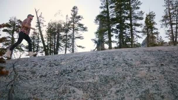 Amazing низький кут пострілу молодий чоловік біг до гігантської скелі в той час як пішохідний туризм на Yosemite National Park повільний рух. — стокове відео