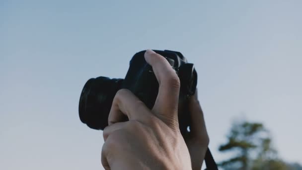 Close-up shot of two photographer hands holding a digital photo camera up outdoors on a sunny clear day slow motion. — Stock Video