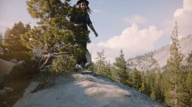 Kamera yosemite milli parkı yavaş hareket keşfetmek büyük kayalar üzerinde yürüyüş mutlu güzel turist kız bacaklar aşağı eğilir.