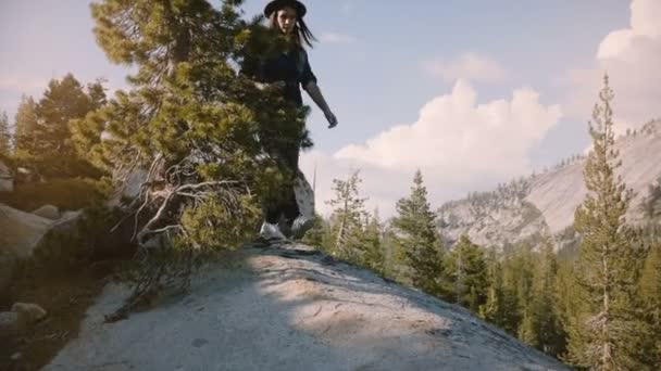 カメラはヨセミテ国立公園のスローモーションを探索する大きな岩の上でハイキング幸せな美しい観光客の女の子の足に傾きます. — ストック動画