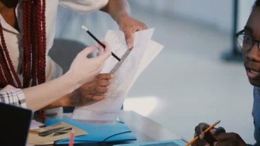 Yakın çekim çok ırklı kalkınma şirketi meslektaşları işbirliği, modern ofis masasında proje sayfası üzerinde beyin fırtınası.