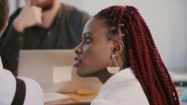 Genç, Afro-Amerikan profesyonel iş kadını başını sallıyor, dinliyor masanın arkasında tartışmayı kabul ediyor..