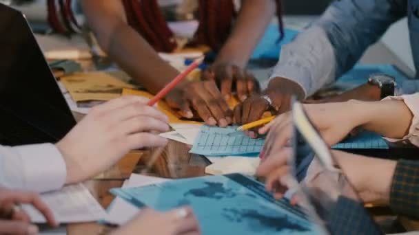 Gros plan sur le processus de travail d'équipe, les partenaires commerciaux multiethniques collaborent sur une grande table de bureau avec des graphiques marketing . — Video