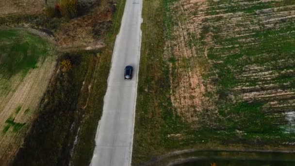 Vista superior aérea, rastreo de cámara de coche negro conduciendo a lo largo de campos erosionados y paso de carretera en viaje por carretera atmosférico . — Vídeo de stock