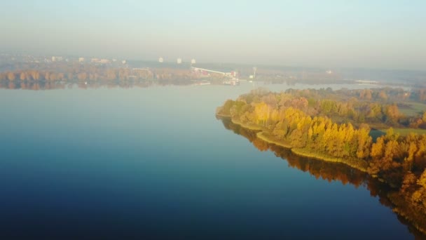 Drone letí nad úžasným jezerem na západ slunce a žlutým podzimním lesem směrem k epické městské obloze. Mírumilovné přírodní Panorama. — Stock video