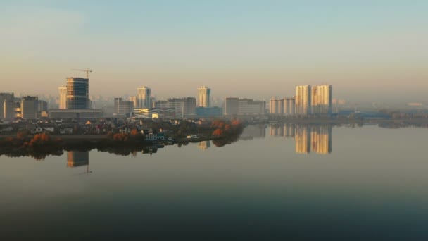 Drohnenflug direkt auf der majestätischen Skyline von Sonnenaufgang in Minsk Weißrussland, Gebäude spiegeln sich im noch herbstlichen See. — Stockvideo