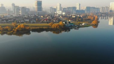 Drone Minsk güzel gündoğumu şehir binaları panorama yaklaşıyor, Belarus hala göl su kenarına yakın gökyüzünü yansıtan.
