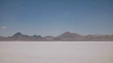Utah inanılmaz Bonneville tuz gölü çölortasında kamera ile sürüş siyah minivan araba yan görünümü çekim.