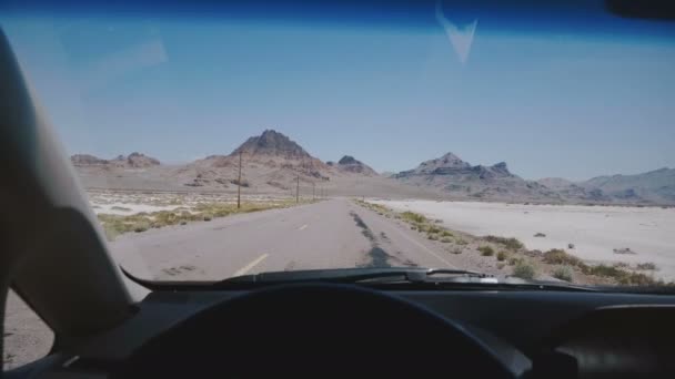 山に向かって壮大な白い塩湖の砂漠の道に沿って運転し、ボンネビルユタ州で澄んだ青い空の地平線に沿って運転する車. — ストック動画