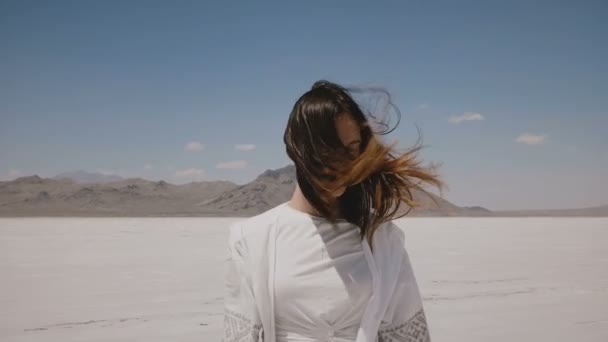 Attractive happy woman in light casual summer clothes posing, walking towards camera at hot salt desert lake in Utah. — Stock Video