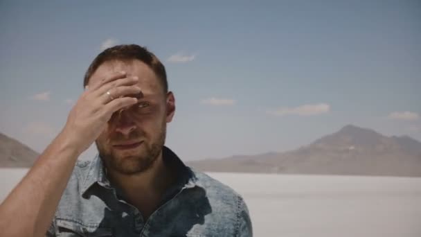 Close-up tiro de homem de meia-idade em roupas casuais olhando ao redor tocando o cabelo no deserto lago de sal seco quente Utah, EUA . — Vídeo de Stock