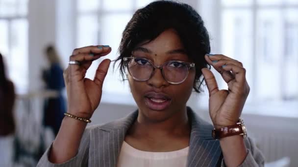 Close-up portrait of professional young African manager business woman adjusting eyeglasses, posing at modern office. — Stock Video