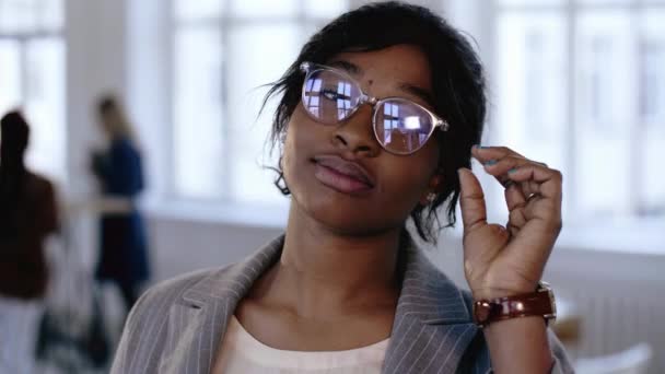 Close-up portrait, professional young African coach business woman touching eyeglasses, looking at camera at office. — Stock Video