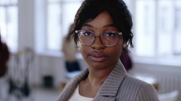 Schöne junge ernsthafte afrikanische Chefin Geschäftsfrau in Brille und formalem Anzug posiert im modernen leichten Loft-Büro. — Stockvideo