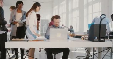 Stresli genç ofis çalışanı adam havada kağıtları atma, meşgul modern ofis masa Kırmızı Destan yürüme.