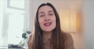 30 'lu yaşlardaki çekici esmer beyaz bir kadının portresi. Konuşuyor, kameraya bakıyor. Web kamerası konferans çağrısı kavramı.