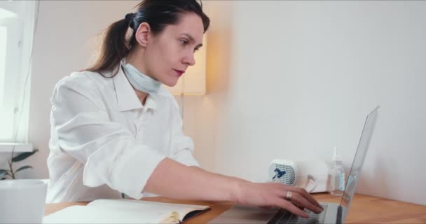 Hermosa mujer médica caucásica profesional feliz consultando a la gente en línea en la conferencia web desde casa usando el ordenador portátil . — Vídeo de stock