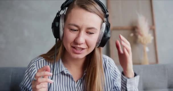 Concept de vidéoconférence. Portrait de heureuse jeune femme blonde souriante dans des conversations écouteurs regardant la caméra web . — Video