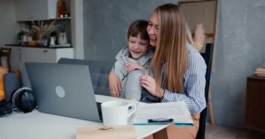 Evde aile eğlencesi. Genç, mutlu bir beyaz anne ve 6-8 yaşındaki oğlu laptopta çizgi film izleyerek vakit geçiriyorlar..