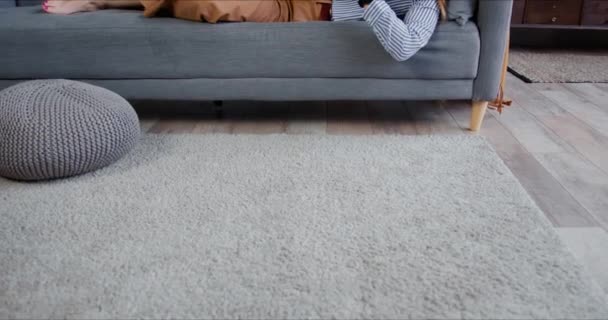 Självisolering. Ung avslappnad vacker blond kvinna rulla flöden på smarttelefon, ler mot kameran på soffan. — Stockvideo