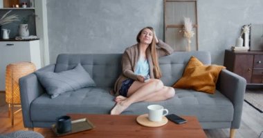 Sıkıntı ve gecikme. Genç, çekici, beyaz, sarışın kadın evde tek başına televizyon izlemekten sıkılmış..