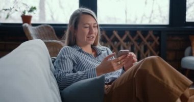 Mutlu, gevşemiş, sarışın, serbest çalışan, internetten alışveriş yapan, evde kendini izole etme uygulaması kullanan bir kadın..