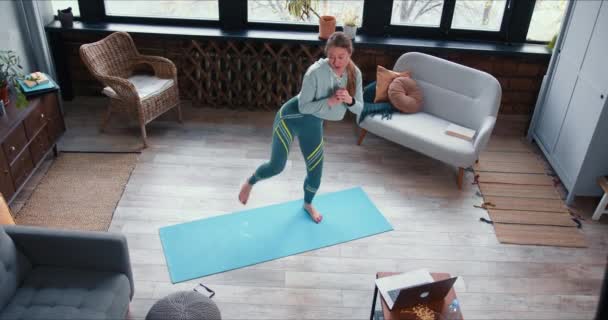 Alto ângulo jovem mulher treinador de fitness loira feliz explicando exercícios de treino on-line usando vídeo laptop em lockdown . — Vídeo de Stock