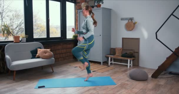 Όμορφη αθλητικός νεαρός Καυκάσιος ξανθιά γυναίκα κάνει άσκηση γυμναστικής στο σπίτι με έξυπνο ρολόι στο κλείδωμα. — Αρχείο Βίντεο