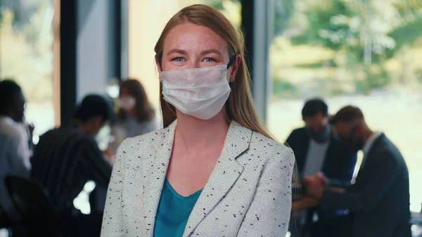 Ochrona przed epidemią. Portret młodej blondynki 30s biznesu kobieta wprowadzenie maski na twarz w nowoczesnym biurze slow motion. — Zdjęcie stockowe