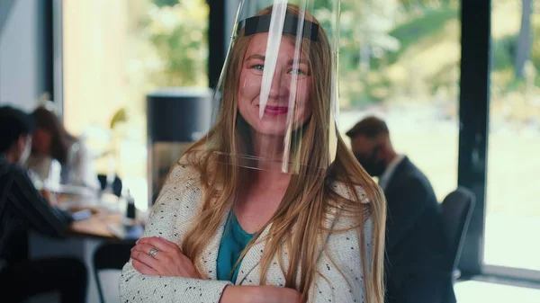 Workplace safety measures. Portrait of young happy business woman wearing plastic face shield at office slow motion.