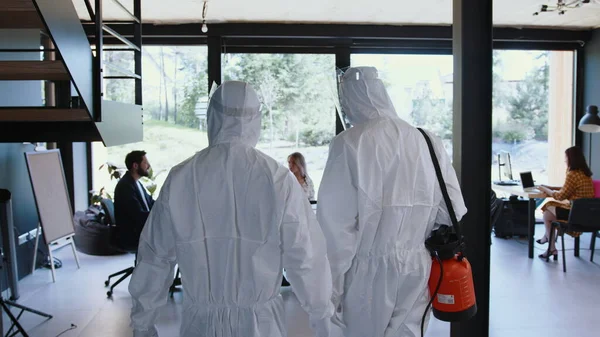 Câmera segue dois profissionais de saúde em ternos médicos brancos entrar em reunião de negócios de escritório, fechá-lo durante COVID-19. — Fotografia de Stock