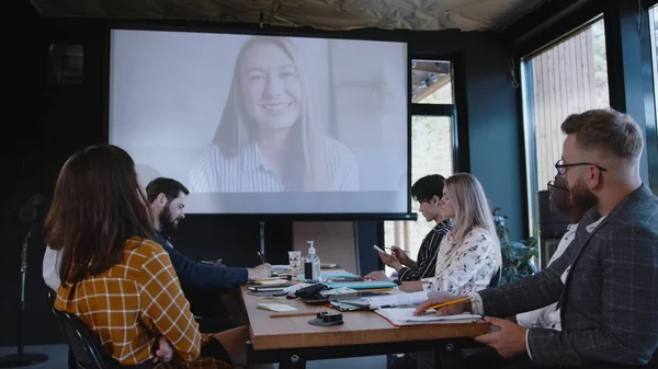 Grupo de personas de negocios multiétnicos que utilizan proyector para la llamada de conferencia web en línea con el entrenador femenino en la oficina moderna. —  Fotos de Stock