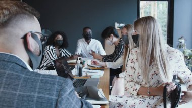 Kamera, ofis ekibi toplantısına katılmadan önce el dezenfektanı kullanan sarışın patron iş kadınını takip ediyor..