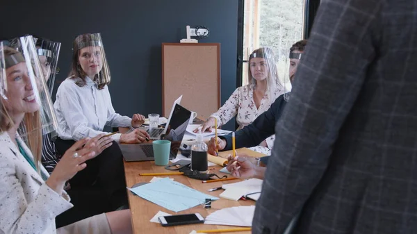 Gente de negocios multiétnicos felices lluvia de ideas juntos en la oficina moderna, todos con escudos faciales protectores COVID-19. —  Fotos de Stock