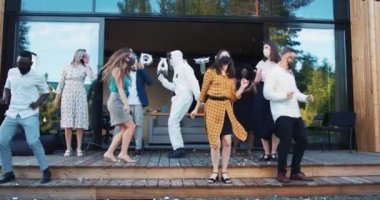 Tecritten sonra yeni normal bir sosyal hayat. Genç mutlu arkadaşlar eğlenceli destansı bir partide COVID-19 güvenlik maskeleriyle dans ediyorlar..