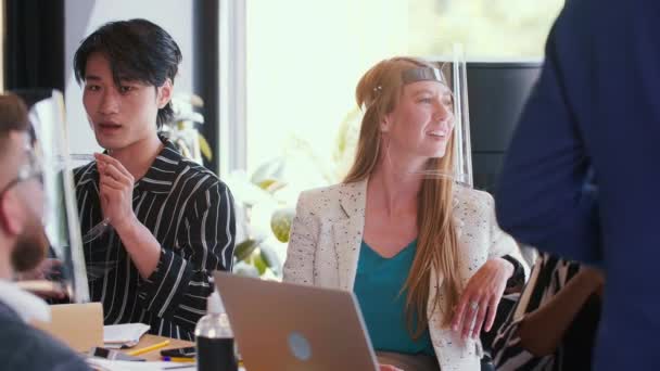 Equipo de jóvenes jóvenes y felices, diversos empresarios, lluvia de ideas en la oficina moderna, todos con escudos faciales COVID-19. — Vídeos de Stock