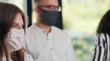 Modern ofiste tıbbi maskeyle poz veren çok ırklı iş arkadaşlarının yakın plan yüzleri..