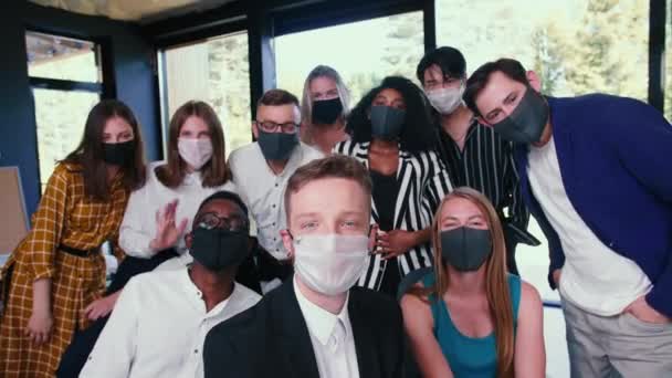 Grupo de felices colegas de negocios diversos posando, saludando para foto selfie en máscaras contra COVID-19 en la oficina moderna. — Vídeos de Stock