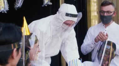 Yeni bir normal olarak tıbbi güvenlik. Arkadaşlar doğum günlerini pasta, konfeti ve plastik COVID yüz kalkanlarıyla kutlarlar..