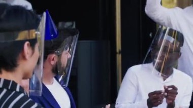 Genç mutlu beyaz adam çeşitli arkadaşlarıyla doğum günü kutlamalarını ve COVID-19 yüz maskesi takan pastayı paylaşıyor..