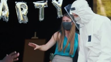 Karantinadan sonra yeni normal bir sosyal hayat. Mutlu çeşitli arkadaşlar COVID-19 güvenlik maskeleri ve kıyafetleriyle eğlenceli bir partide dans ediyor..