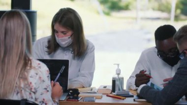 COVID-19 'dan sonra modern ofiste iş akışı. Ofiste yüz maskeleriyle çalışan çok ırklı profesyonel genç yöneticiler.