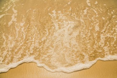 Güneş ışınları ile ıslak sarı kum üzerinde dalga okyanus