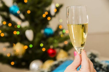 Çam ağacı arka plan üzerinde kadın elinde köpüklü şampanya