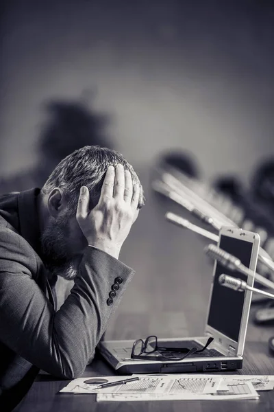 Sad businessman with beard working in office and covering his face