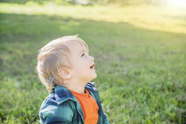 Güneşli bir gün yeşil çim arka planda küçük sarışın çocuk