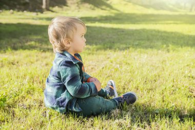 Güneşli bir gün yeşil çim arka planda küçük sarışın çocuk