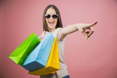 Alışveriş çantaları tutan güneş gözlüğü takan heyecanlı güzel bir kız portresi 