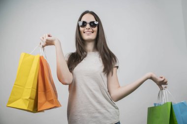 alışveriş çantaları tutan güneş gözlüğü giyen güzel kız 